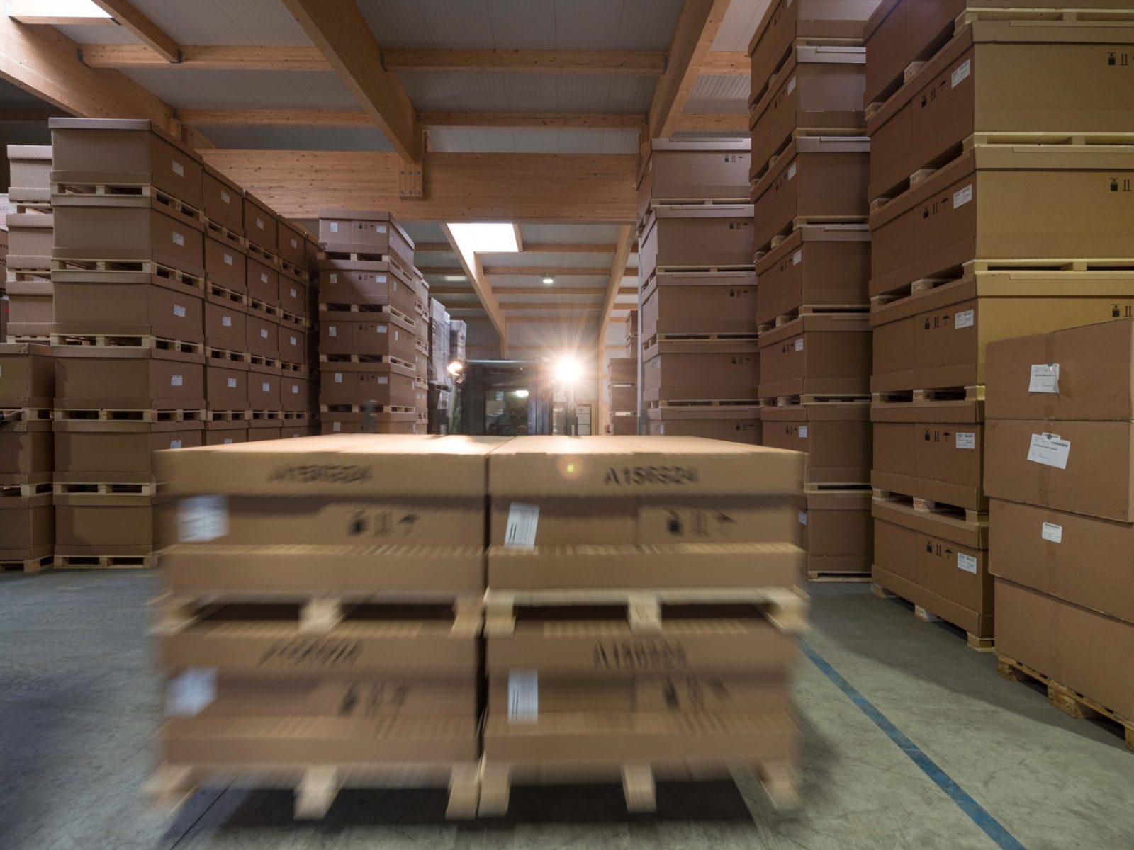 Lagerhalle mit gestapelten Kartonverpackungen und innerbetrieblichem Transport
