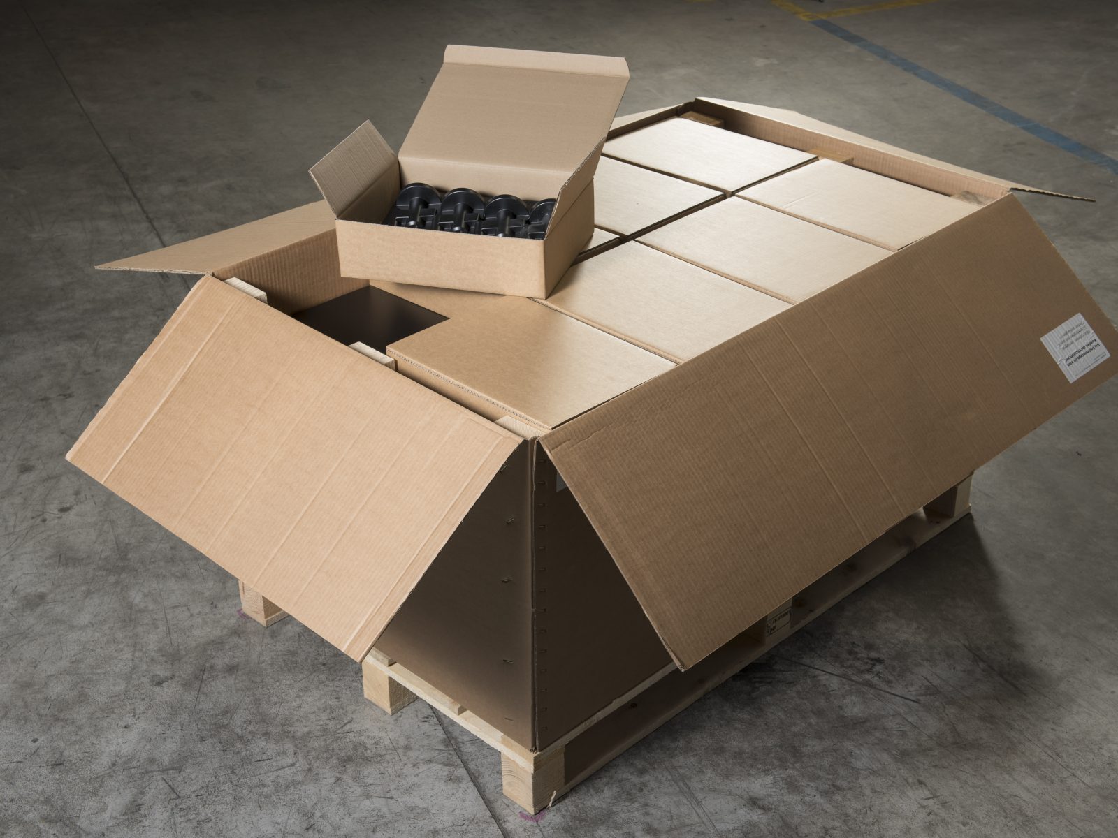 Geöffnete Kartonverpackung mit passgenauem Innenleben auf einer Palette