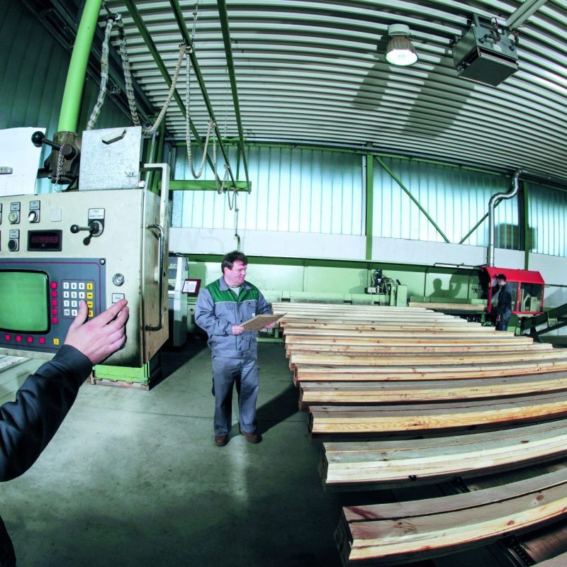Mitarbeiter bearbeiten Holzplatten an einer Maschine im AGROPAC-Werk