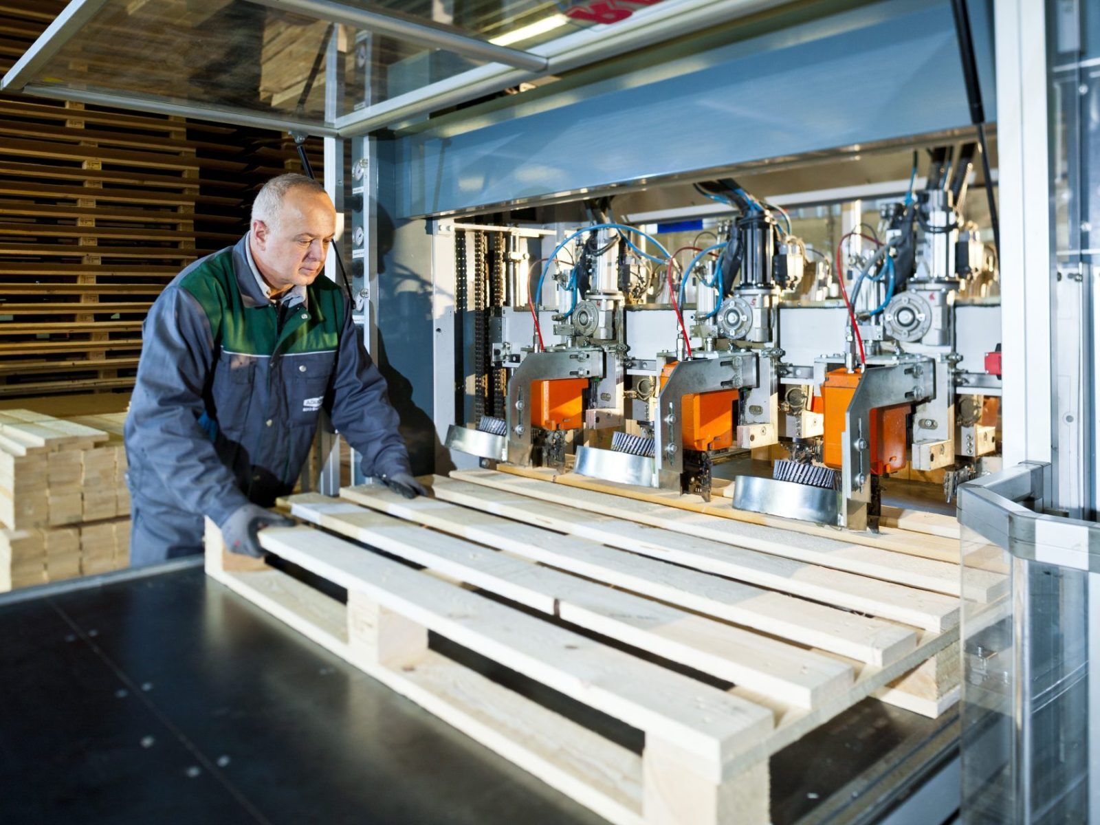 Mitarbeiter fertigt eine Holzpalette an einer Produktionsmaschine